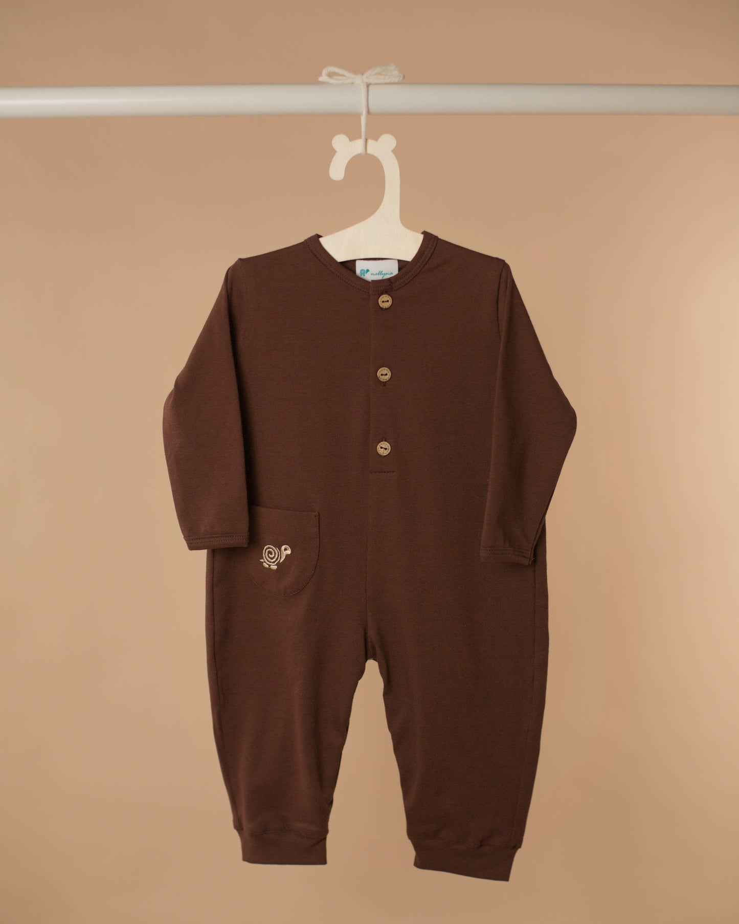 Baby romper in cocoa color displayed against beige background