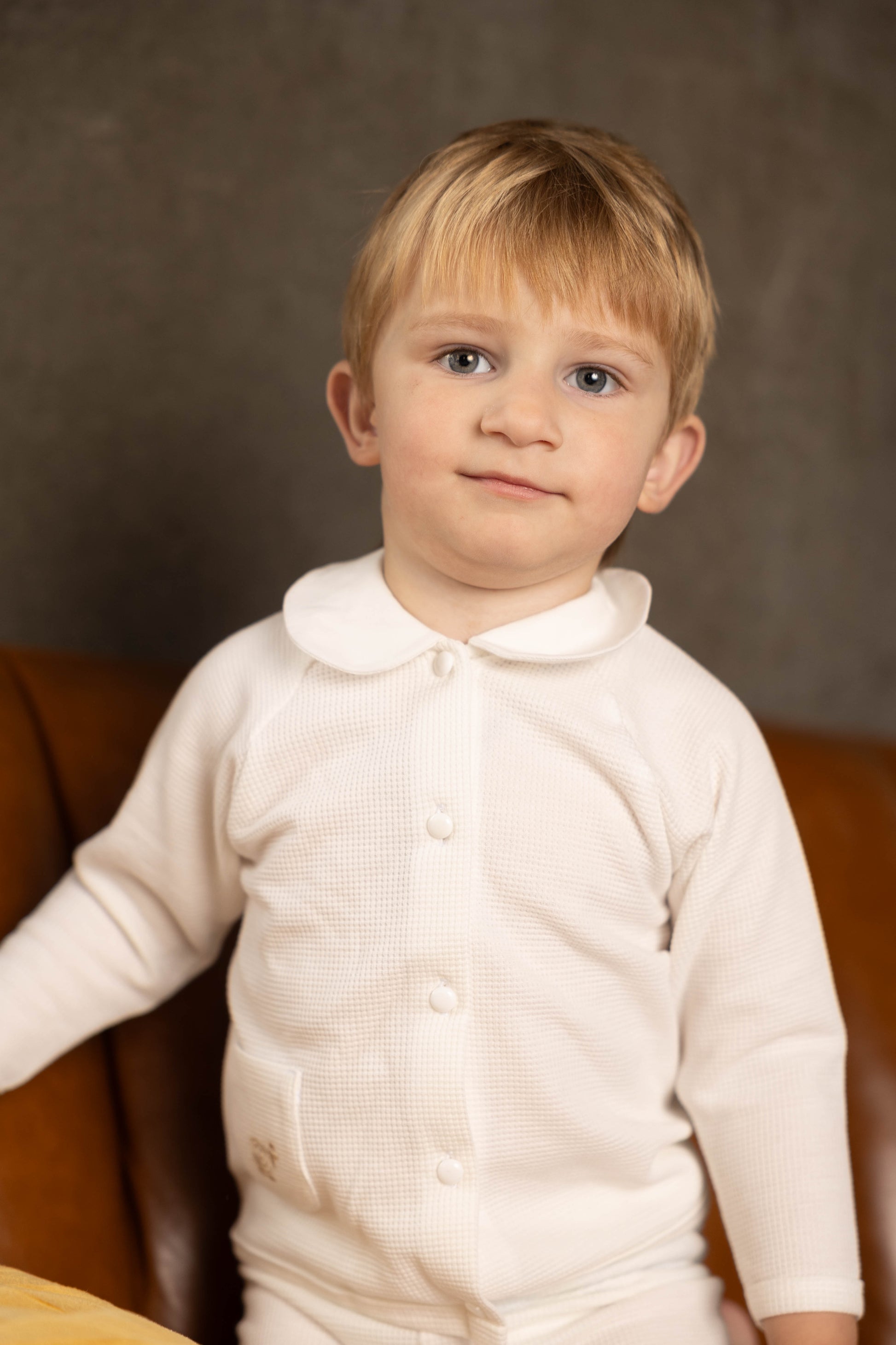 Young child wearing a white waffle set against a brown background