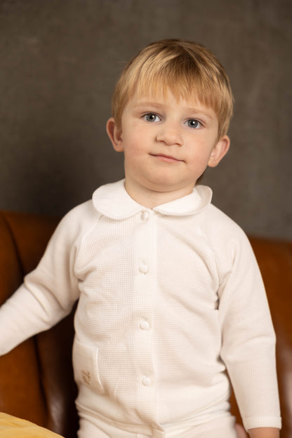 Young child wearing a white waffle set against a brown background