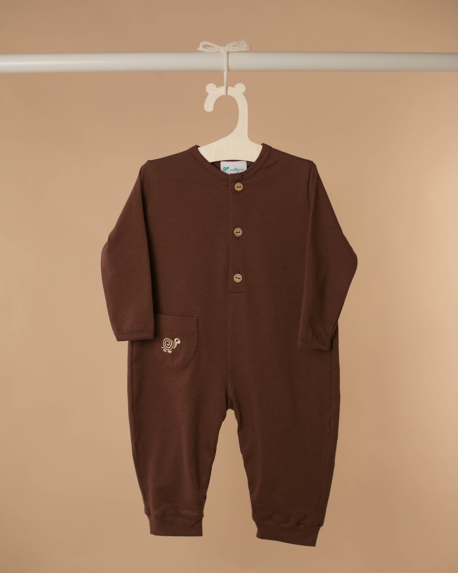 Baby romper in cocoa color displayed against beige background